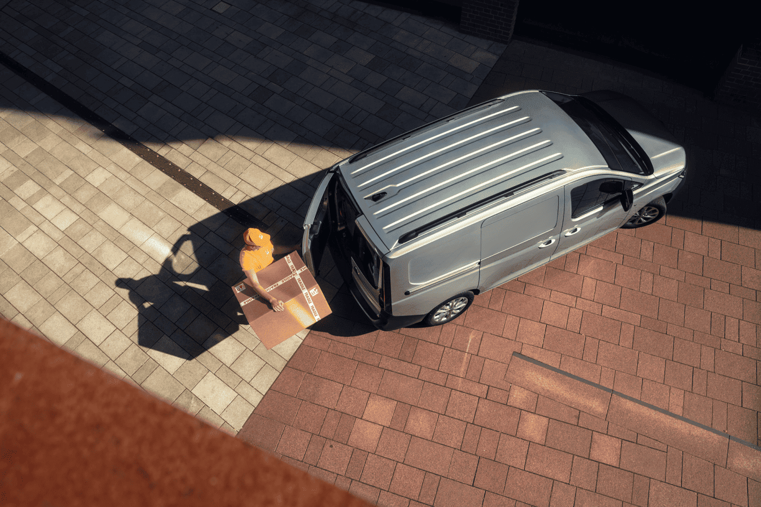 Kurier wyjmuje paczkę z Volkswagena Caddy Cargo.