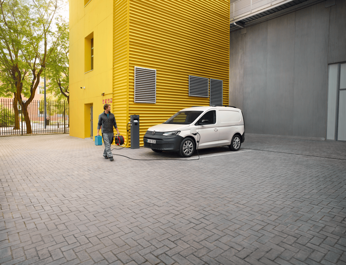 Widok na VW Caddy Cargo z silnikiem PHEV, podpiętego do ładowarki