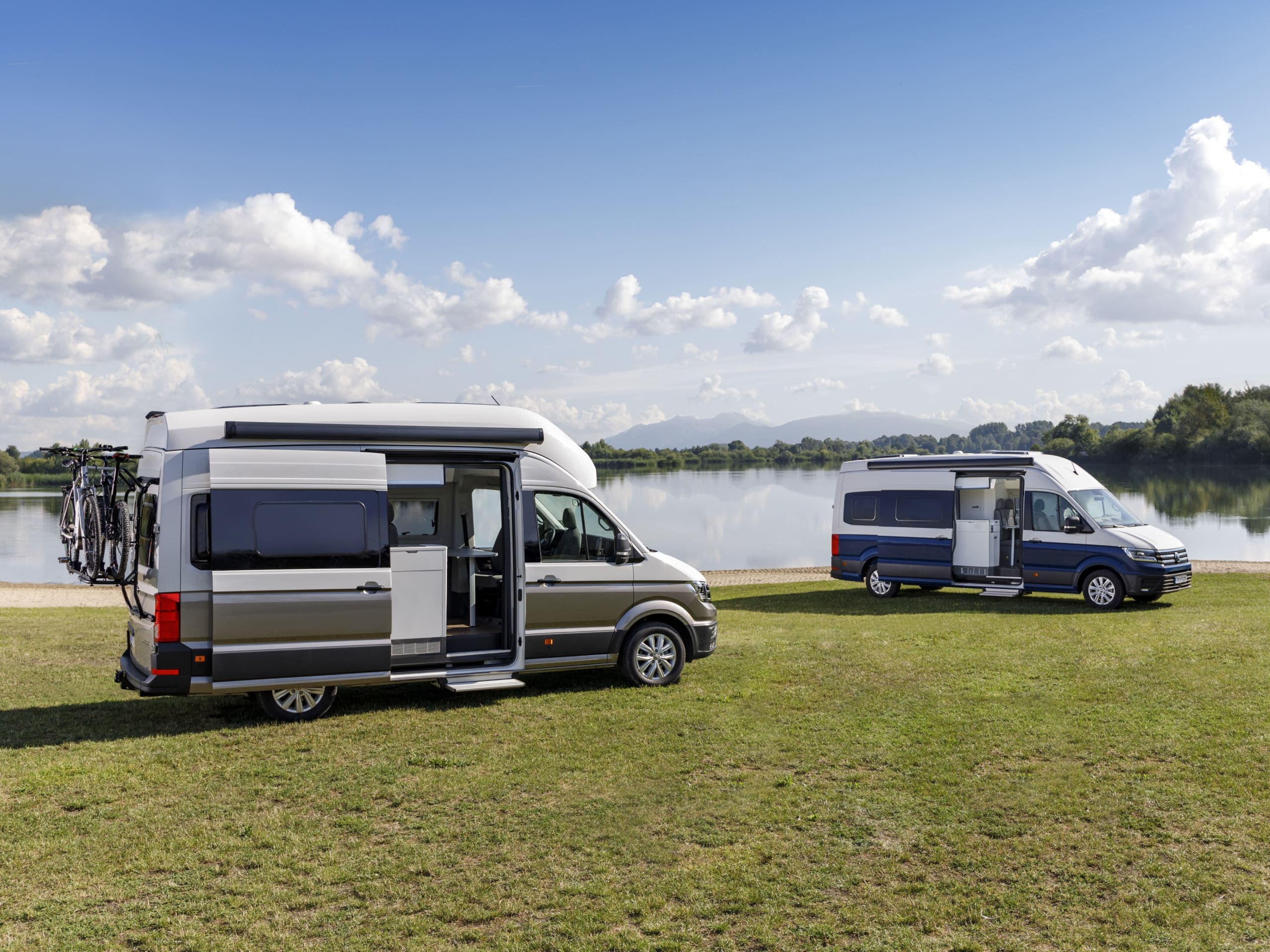 Dwa Volkswageny Grand California stoją na brzegu jeziora. 