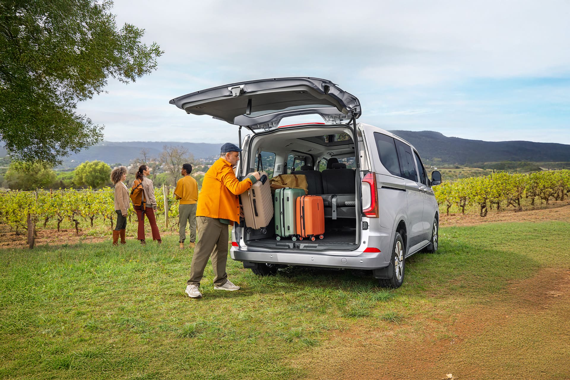 Mężczyzna pakuje walizki do bagażnika Volkswagena Caravelle.